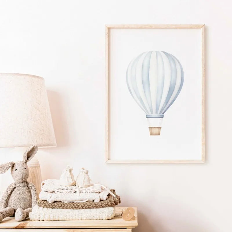 Framed artwork of a hot air balloon on a wall above a wooden surface with toys and blankets.