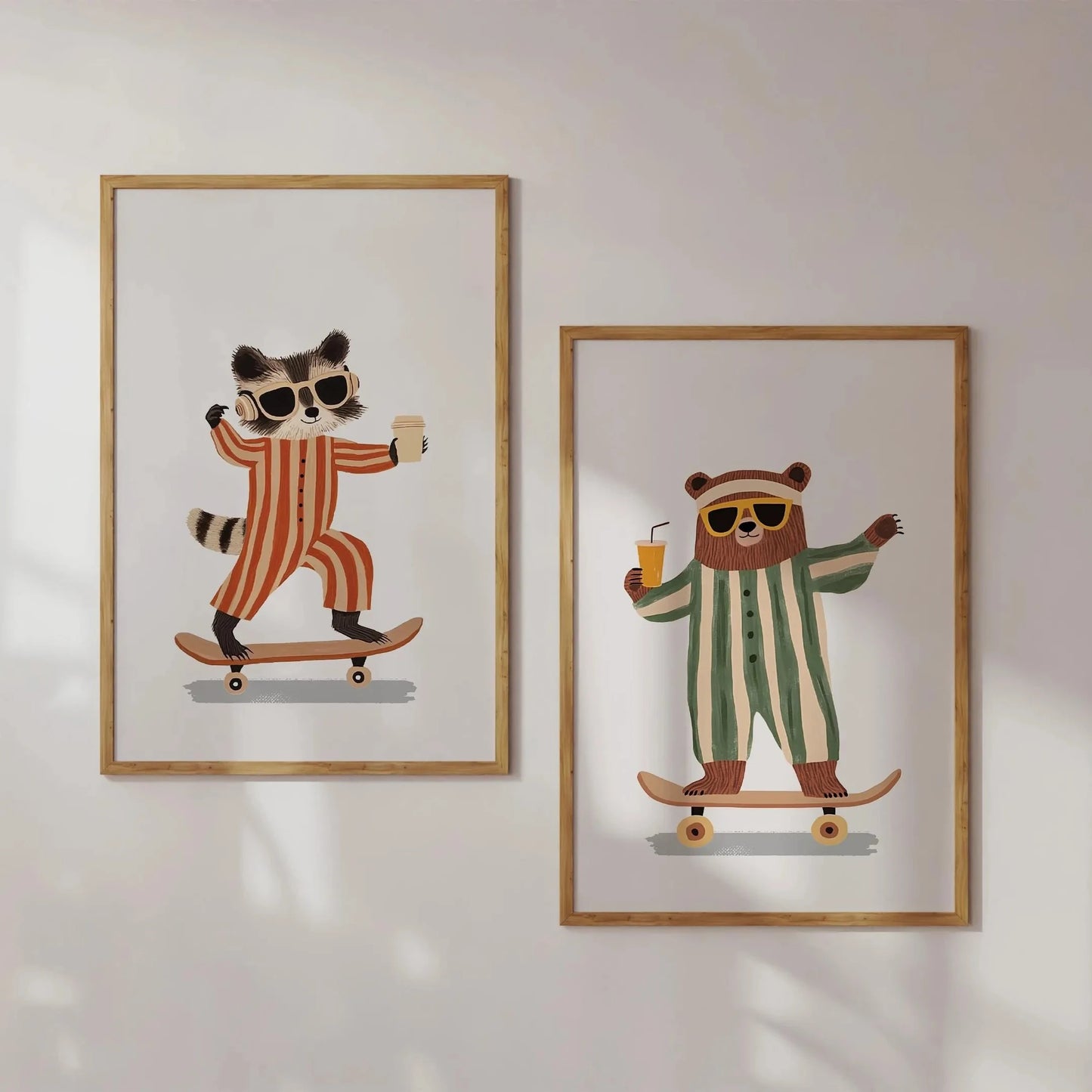 Two framed illustrations of a raccoon and a bear on skateboards with sunglasses and drinks, on a white wall.