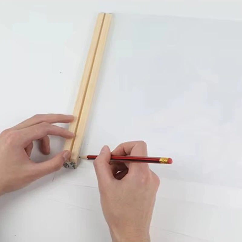 Person using a red pencil to mark a wooden stick on a white background