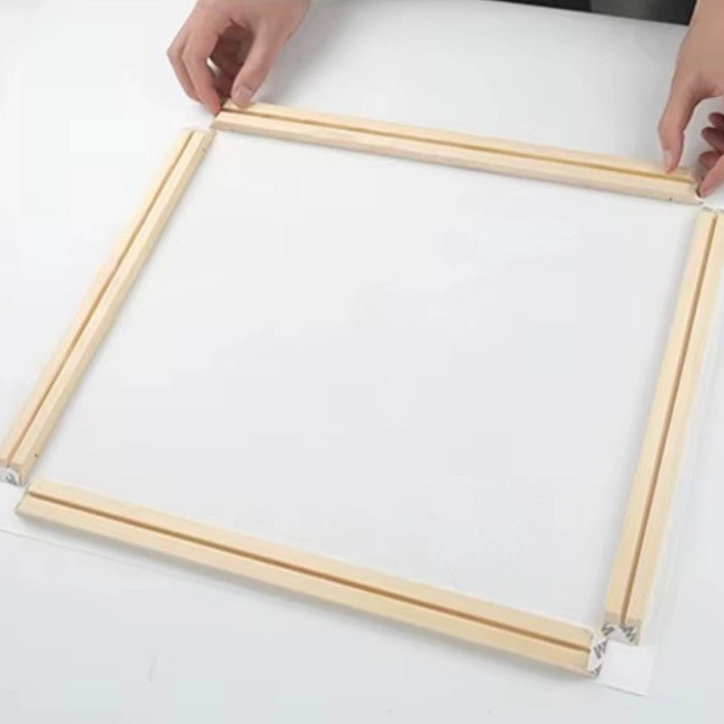 Wooden picture frame being held together by two hands on a white background