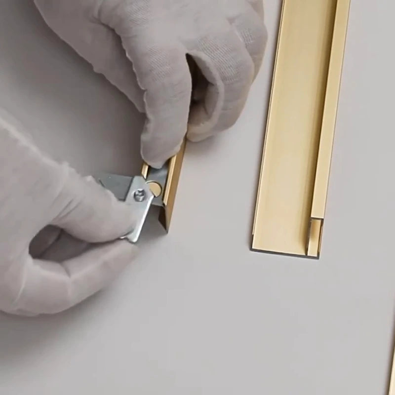 Person wearing gloves using a tool to work on a gold object on a light gray background