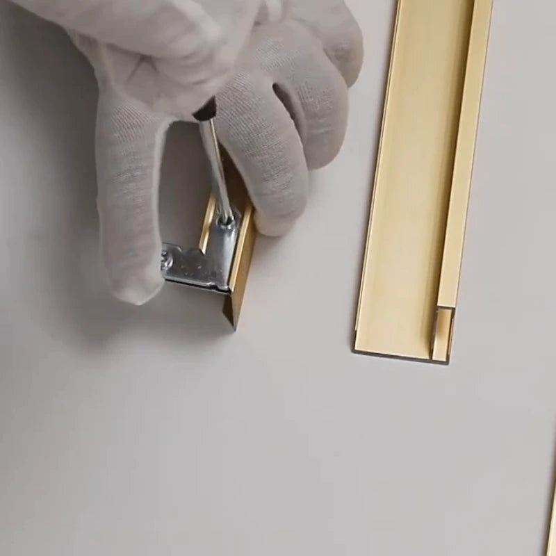 Hand wearing a white glove applying a gold trim strip to a surface.