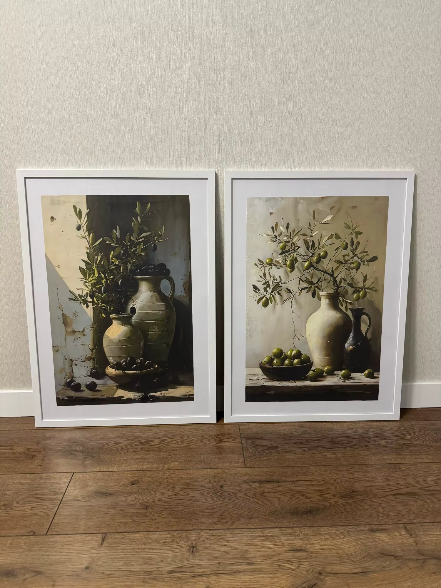Two framed prints of a still life scene with a vase and fruit on a wooden floor.