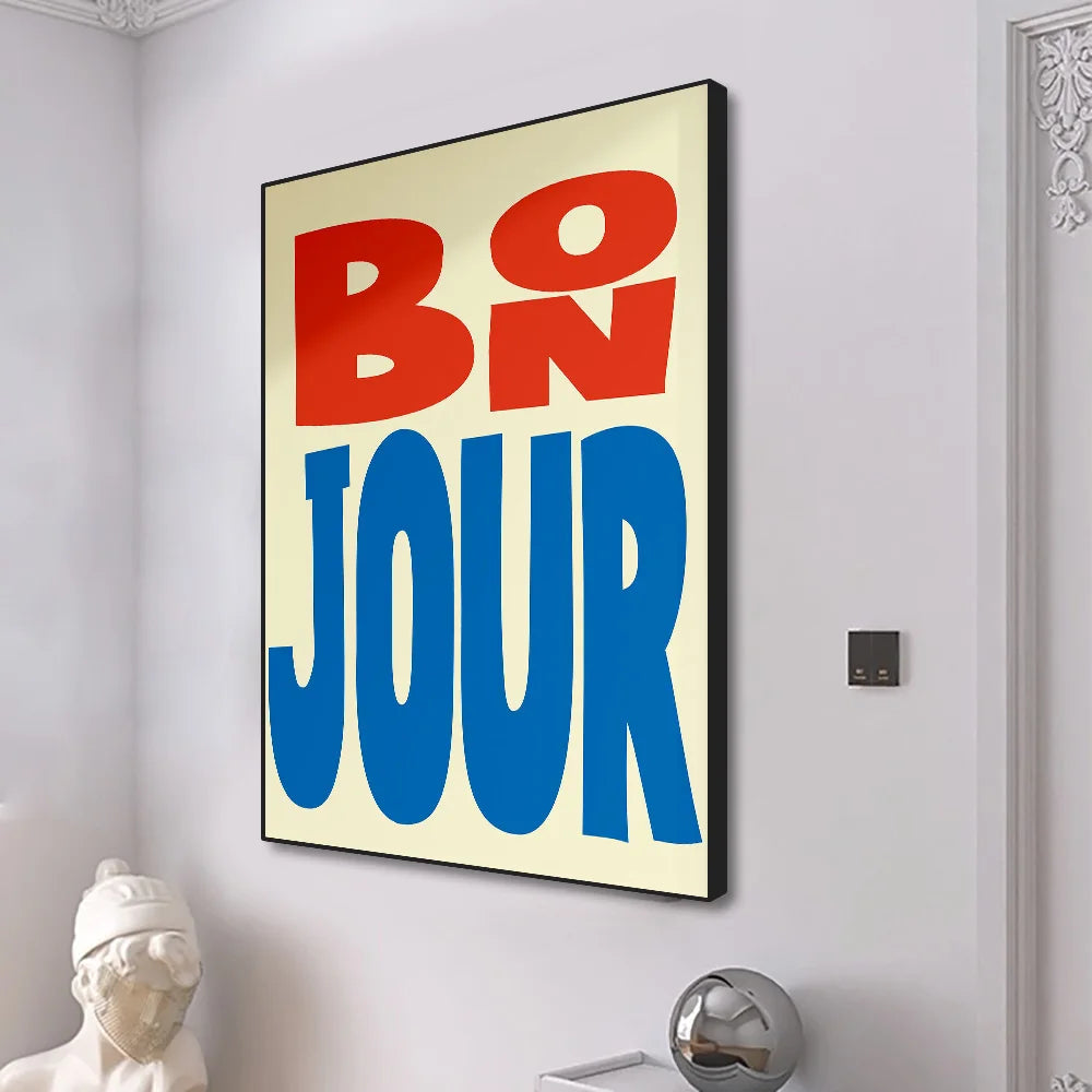 Decorative wall art with 'BO N JOUR' text in red and blue on a beige background, mounted on a white wall.