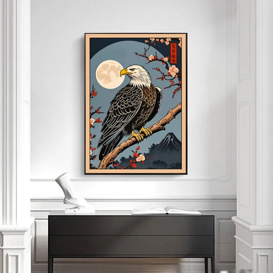 Framed artwork of an eagle on a branch with cherry blossoms and a moon in the background, displayed on a wall above a desk. Canvas & Curio