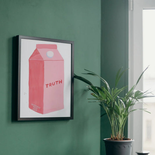 Framed artwork of a pink milk carton with 'TRUTH' on a green wall, next to a potted plant. Canvas & Curio