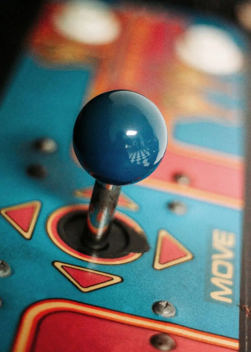 Close-up of an arcade joystick with colorful buttons on a blurred background