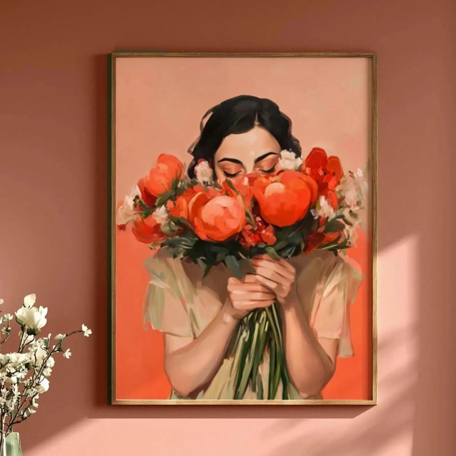 Framed artwork of a woman holding red flowers against a peach-colored wall.