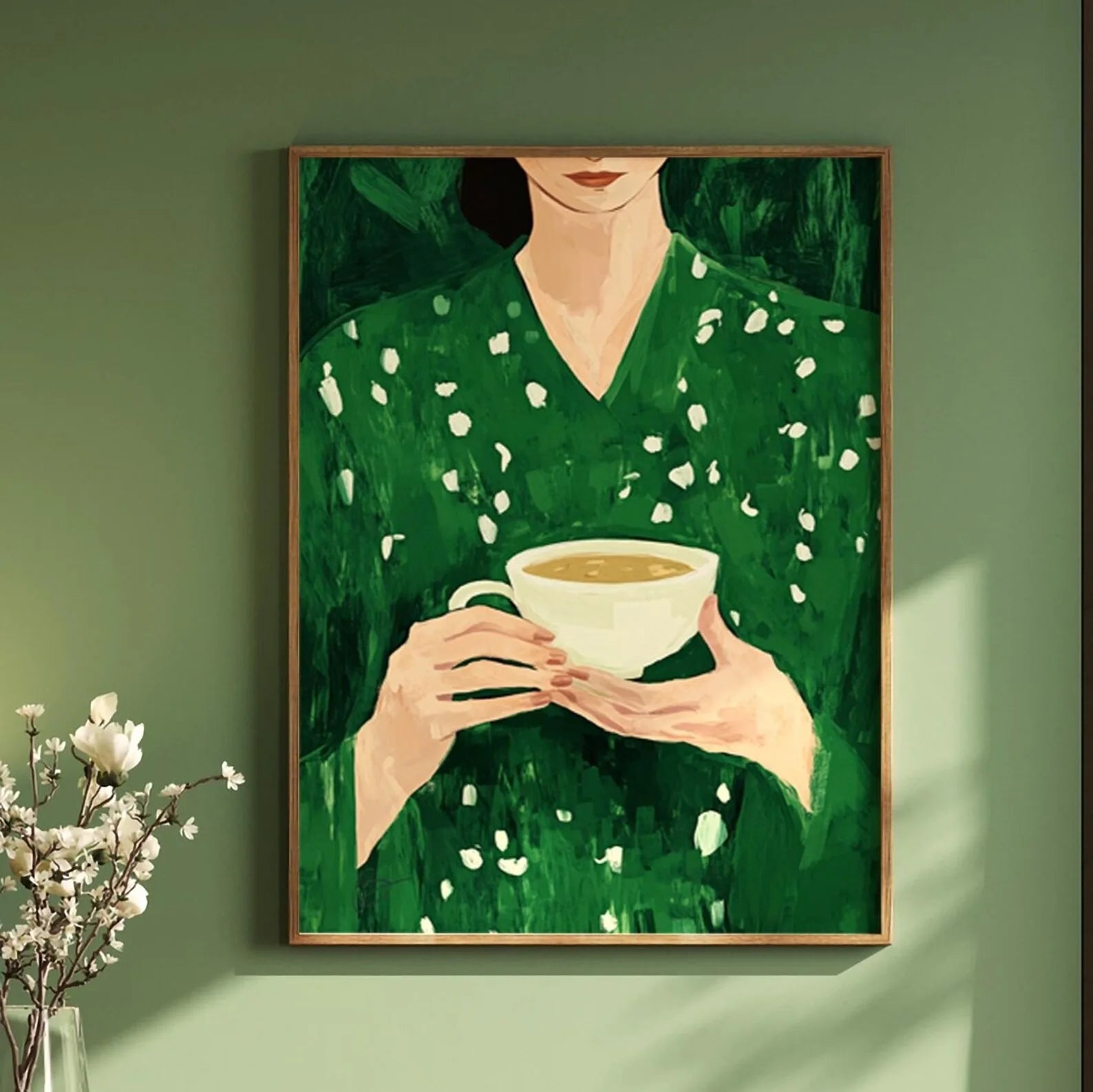Framed artwork of a person in a green dress holding a cup against a green wall.