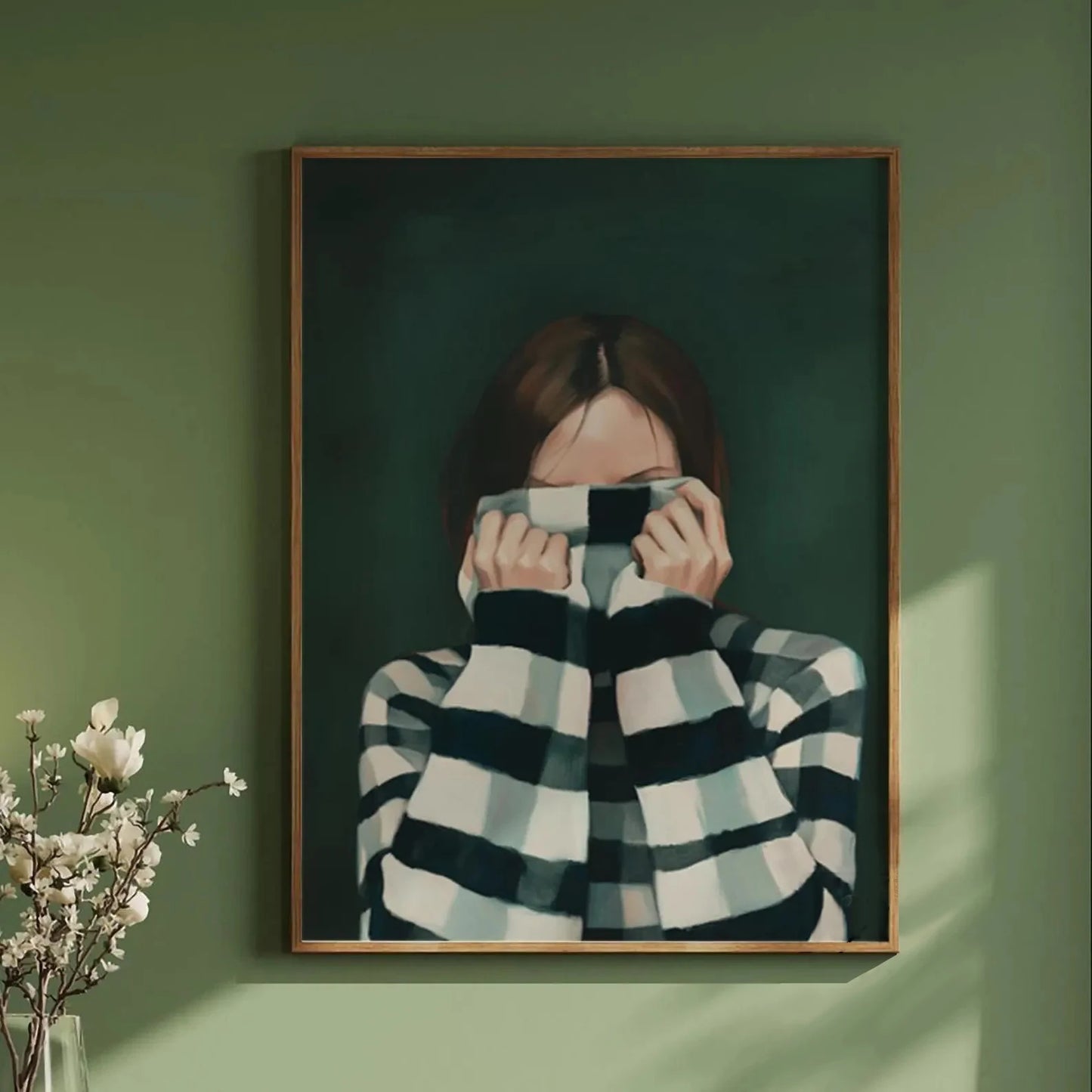 Framed artwork of a person wearing a checkered sweater on a green wall.