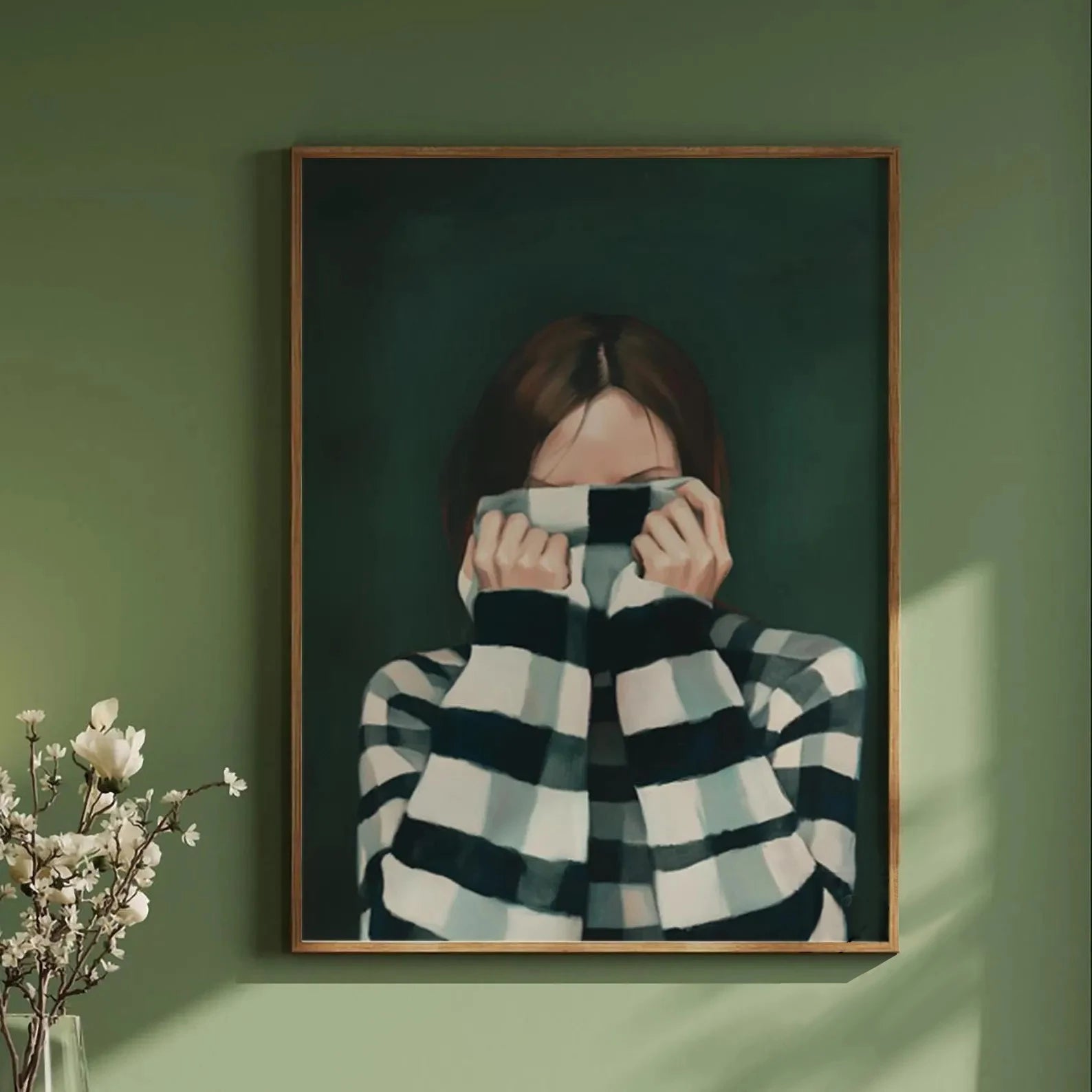 Framed artwork of a person wearing a checkered sweater on a green wall.