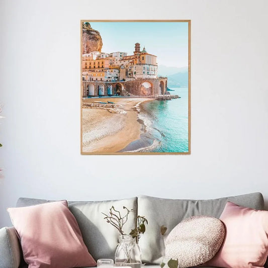 Framed artwork of a coastal scene above a sofa with decorative pillows. Canvas & Curio