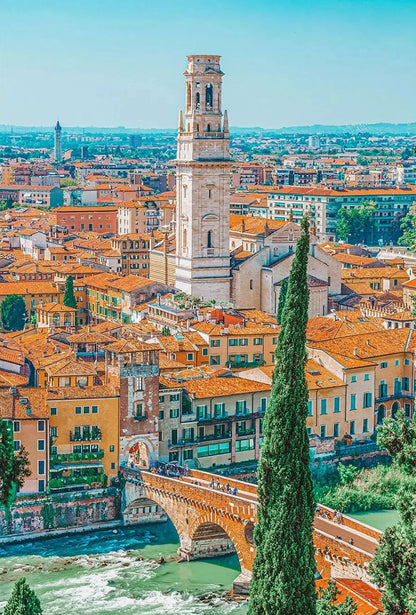 Cityscape with a tall tower and a river, featuring buildings with orange roofs.