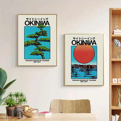 Two framed posters of Okinawa on a wall above a dining table with plants and books.