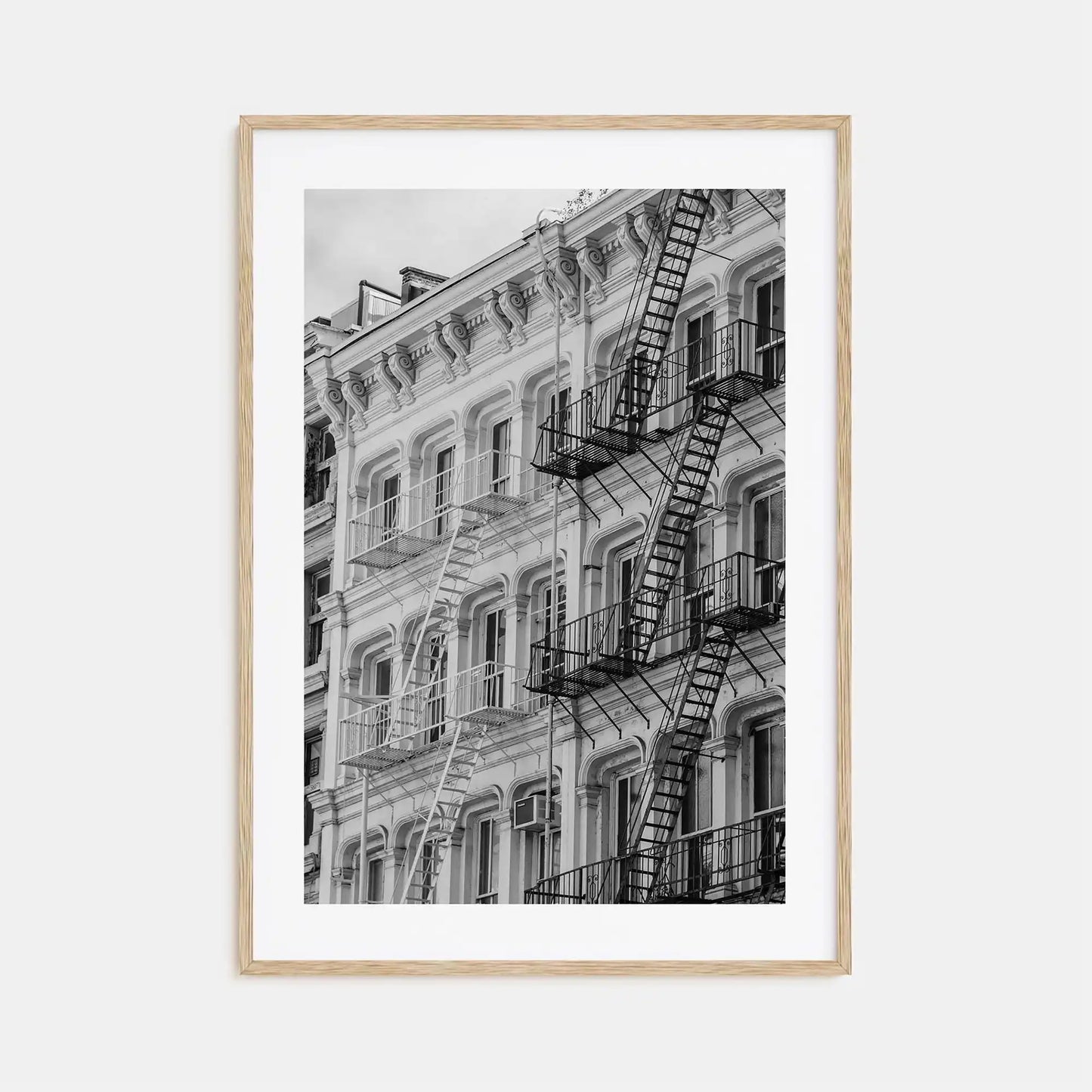Framed black and white photograph of a building with fire escapes on a light gray background
