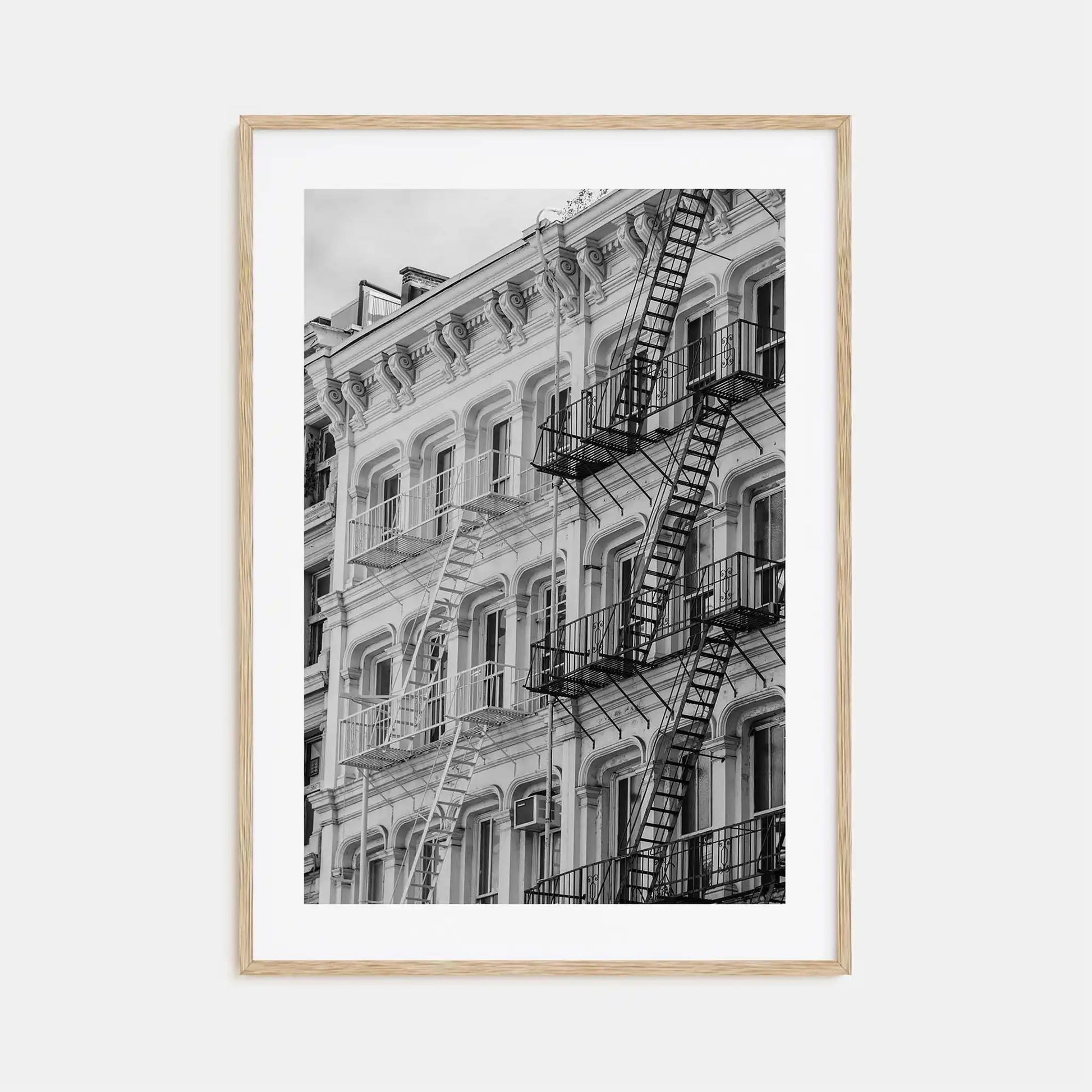 Framed black and white photograph of a building with fire escapes on a light gray background