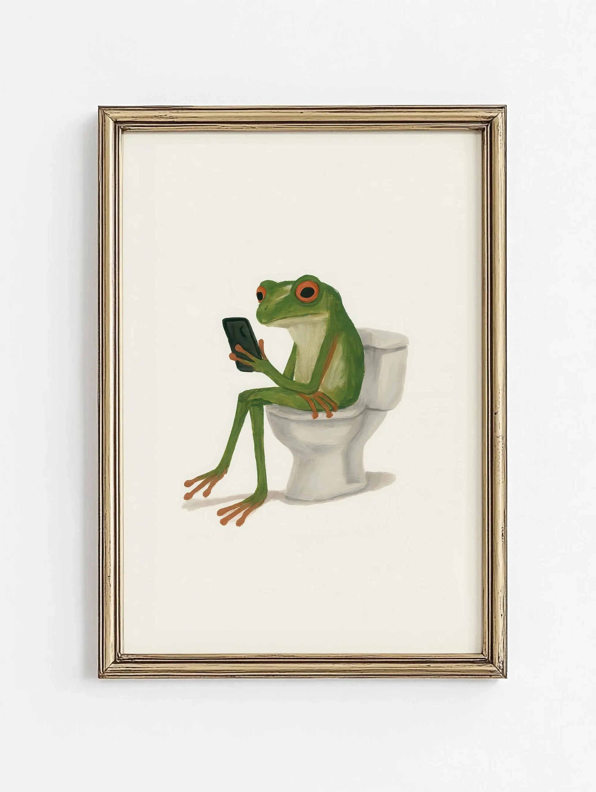 Framed artwork of a frog sitting on a toilet using a smartphone.