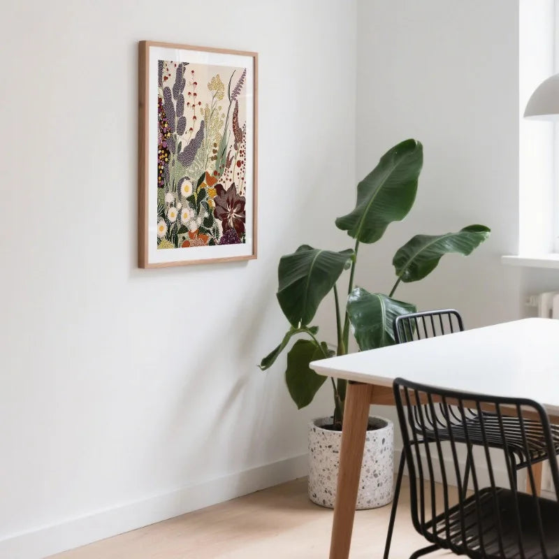 Modern interior with a framed floral print on the wall, a plant, and a dining table with chairs.