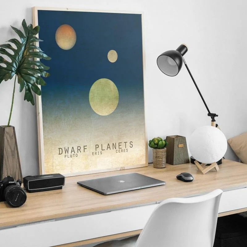 Modern office desk with a poster of dwarf planets, lamp, and laptop.