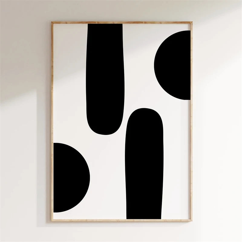 Framed abstract art with black shapes on a white wall