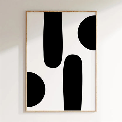 Framed abstract art with black shapes on a white wall