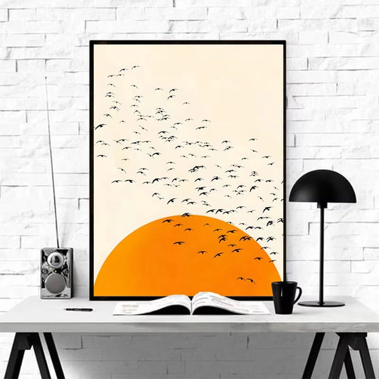 Framed artwork of birds flying over an orange sunset on a white wall. Canvas & Curio