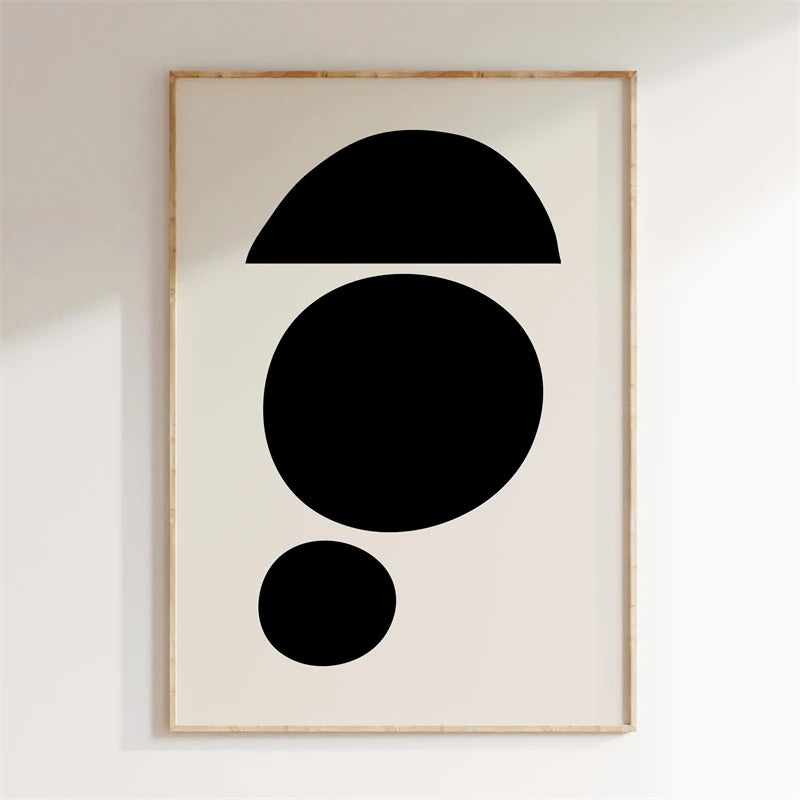 Framed abstract art with black shapes on a white wall
