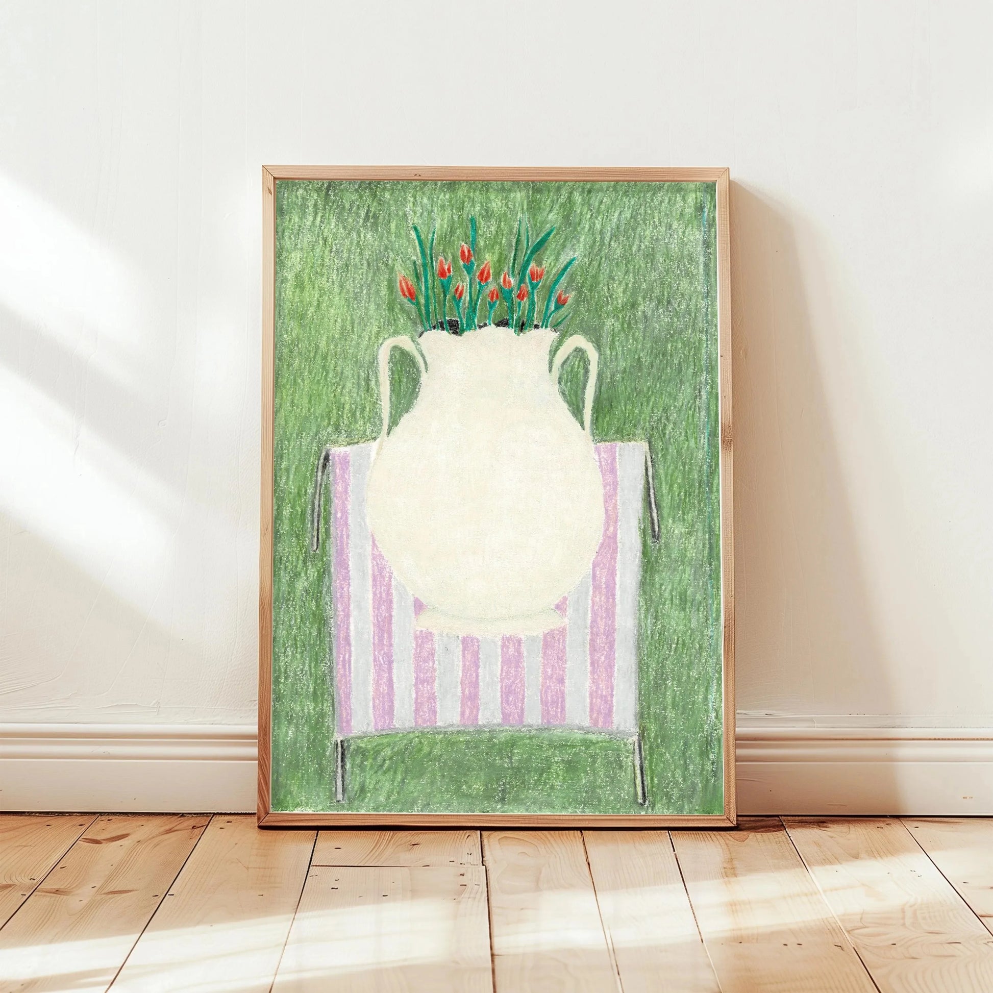 Framed artwork of a white vase with red flowers on a green background, displayed on a wooden floor.