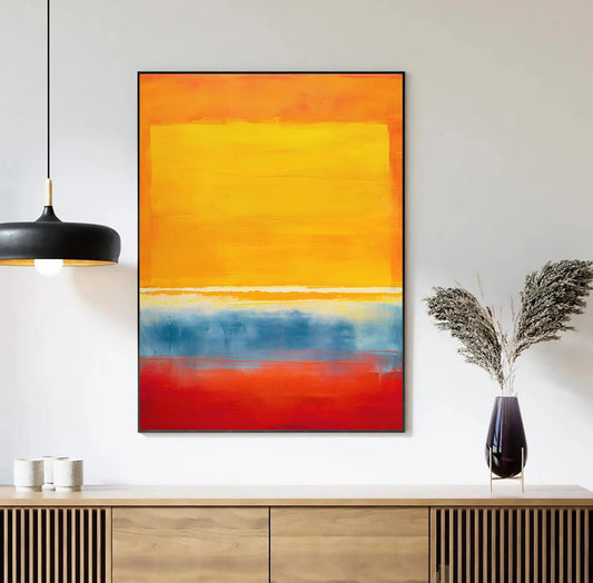 Abstract art painting with orange, yellow, and red colors on a white wall above a wooden cabinet. Canvas & Curio