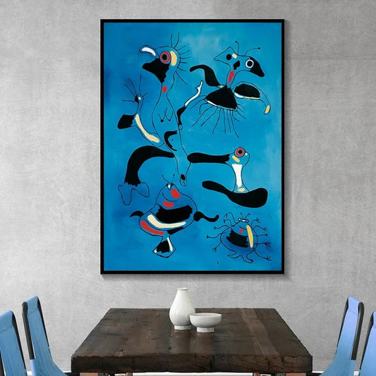 Abstract artwork of fish on a blue background in a black frame, hanging above a wooden table with blue chairs. Canvas & Curio