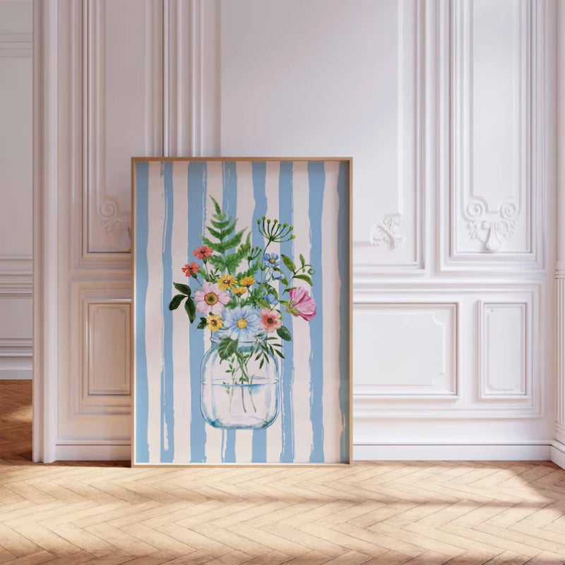 Framed artwork of a floral arrangement in a jar with blue and white striped background on a wall.