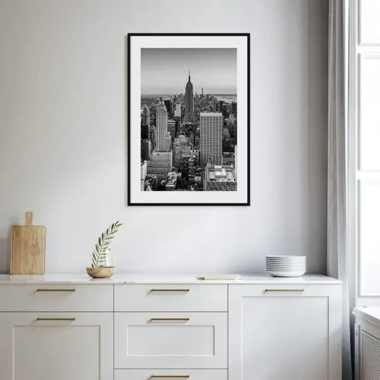 Framed black and white cityscape print on a wall above a white cabinet. Canvas & Curio