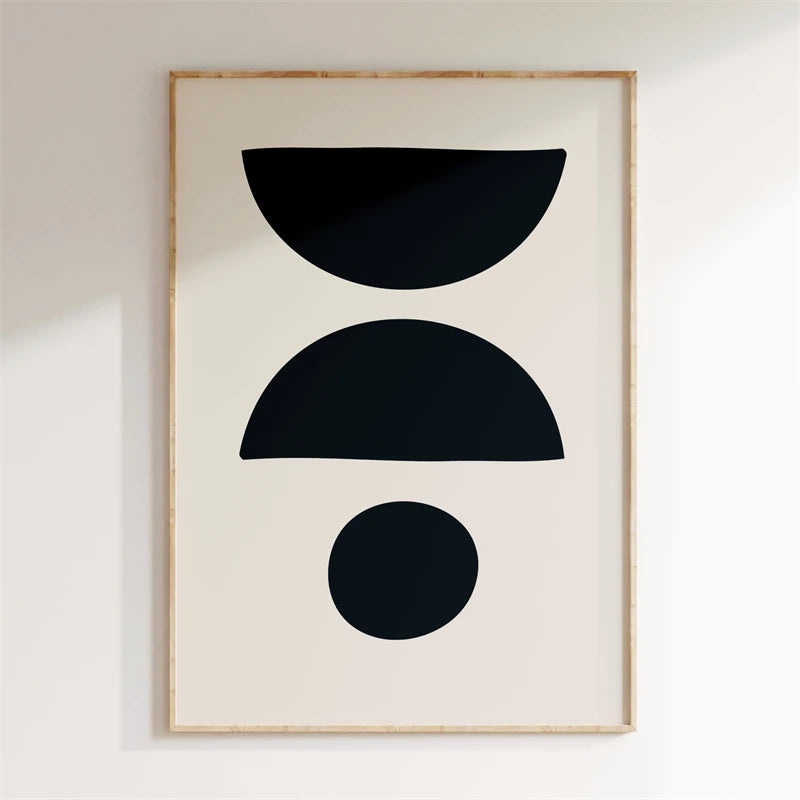 Framed abstract art print with black shapes on a white wall