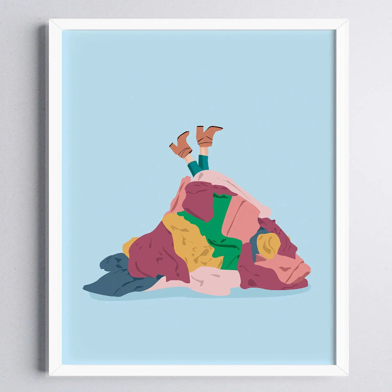 Framed artwork of a person lying on a pile of colorful clothes against a light blue background.