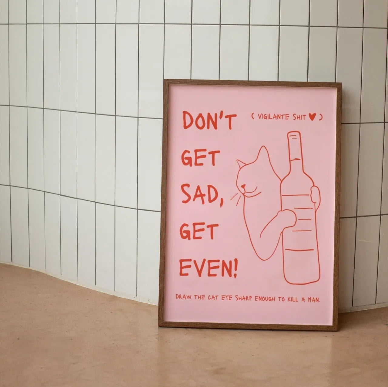 Framed poster with a pink background and text and a cat illustration on a tiled wall.