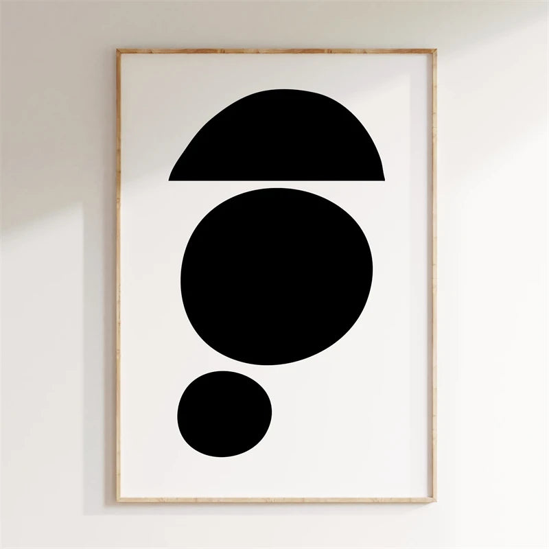 Framed abstract art with black shapes on a white wall
