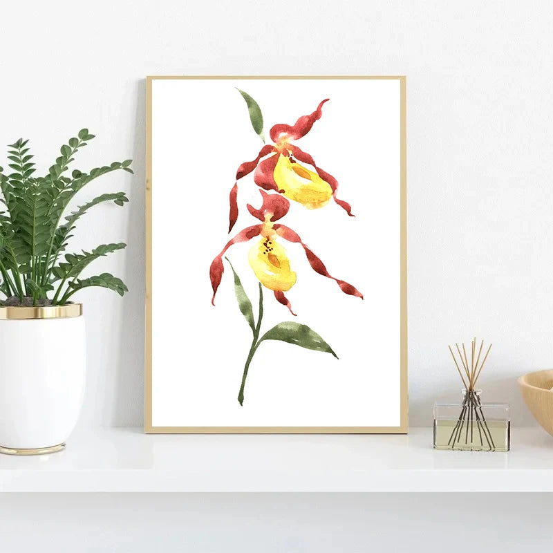 Framed artwork of red and yellow flowers on a white wall with a plant and decorative items below.