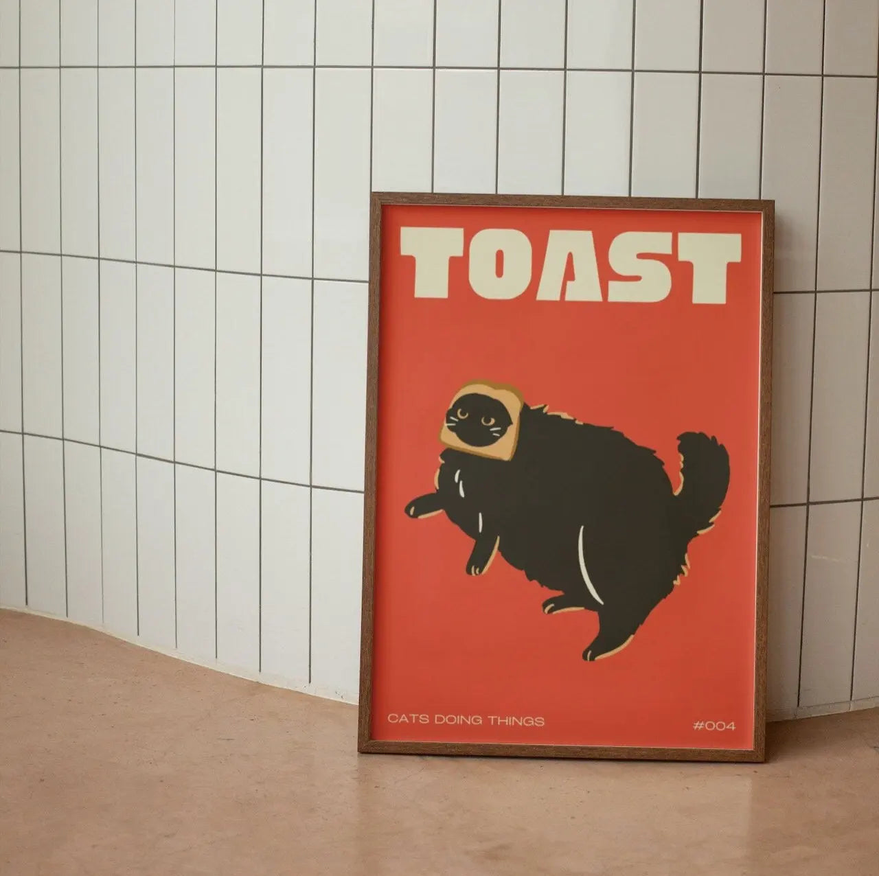 Poster with a cat wearing a helmet and the word 'TOAST' on a red background, leaning against a tiled wall.
