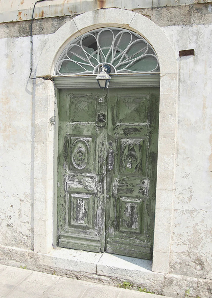 Old wooden door with decorative glass above it on a stone building