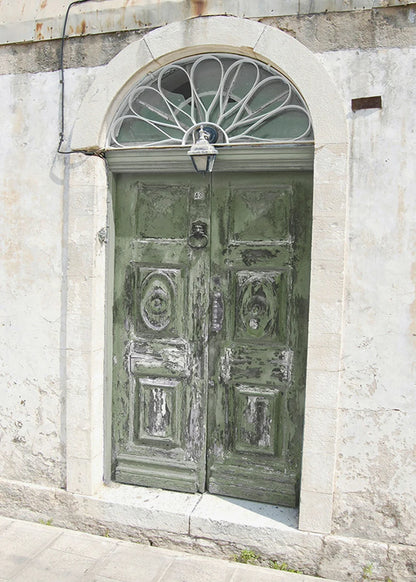 Old wooden door with decorative glass above it on a stone building