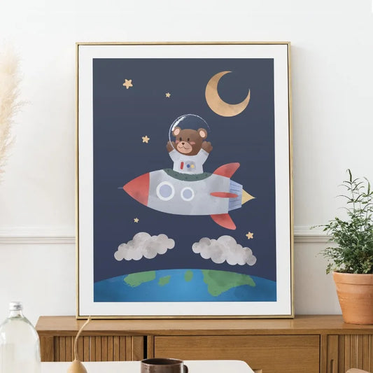 Framed children's poster of a bear astronaut on a rocket with Earth and moon in the background. Canvas & Curio
