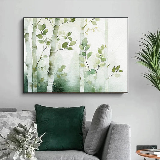 Framed artwork of green leaves on a wall above a gray sofa with green cushions. Canvas & Curio
