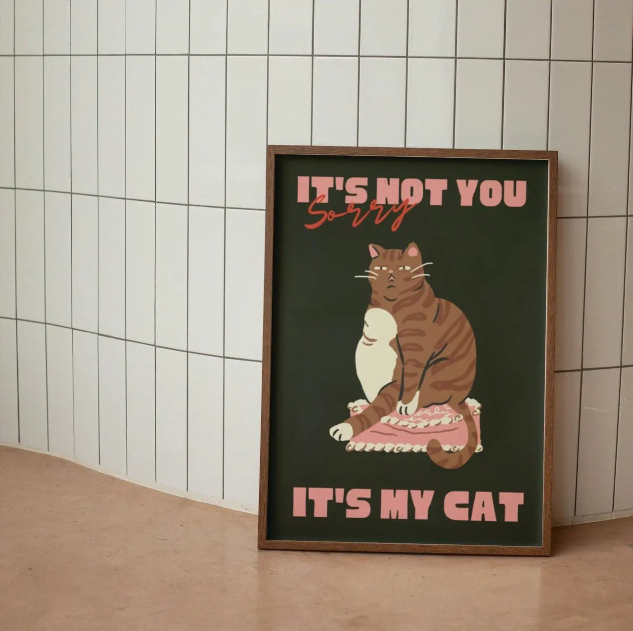 Framed artwork with a cat illustration and text on a tiled wall background