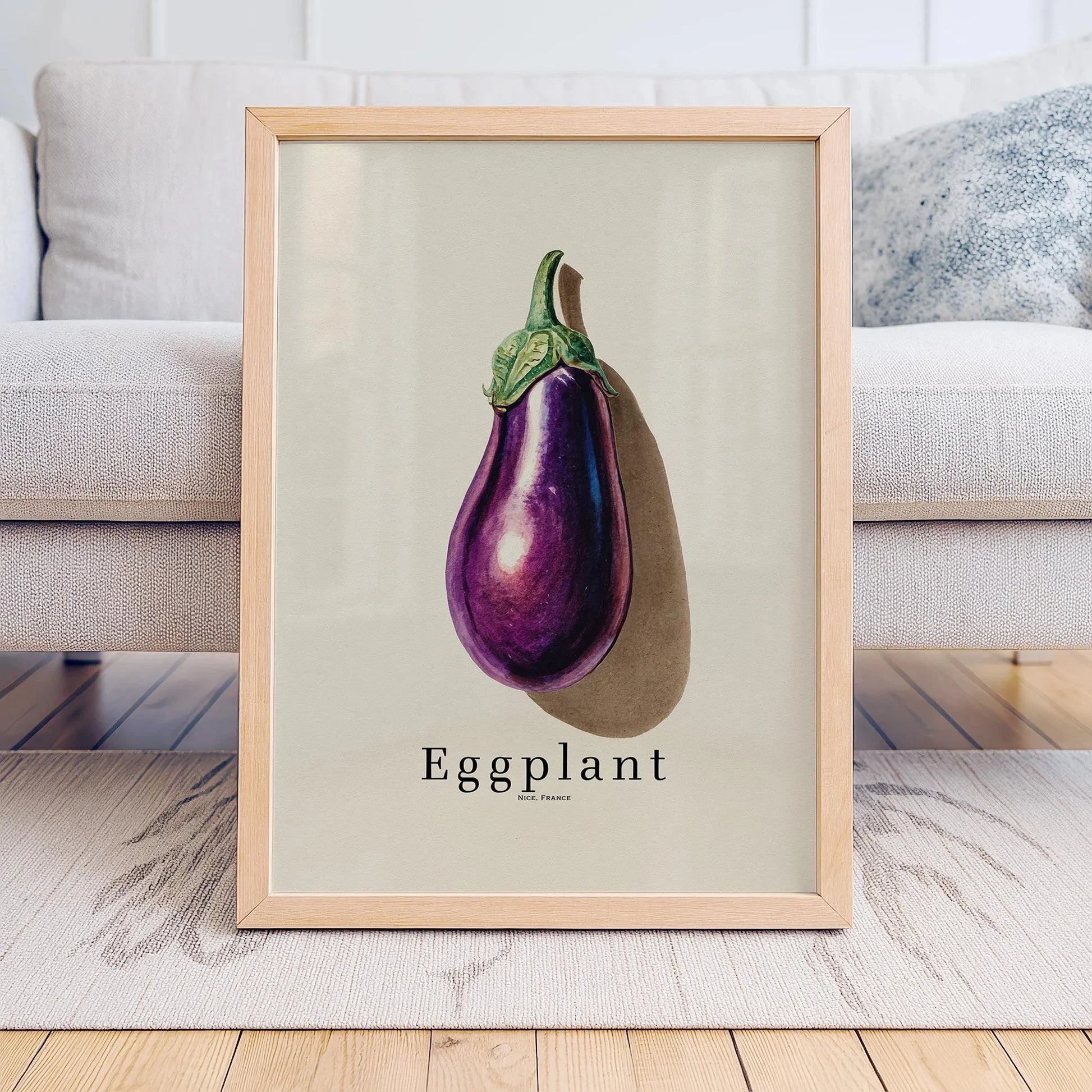 Framed print of an eggplant on a light background, displayed in a room with a couch.