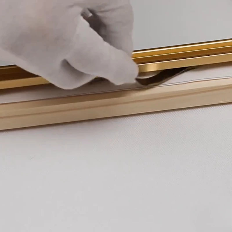 Gold frame being adjusted with a white cloth on a light gray background