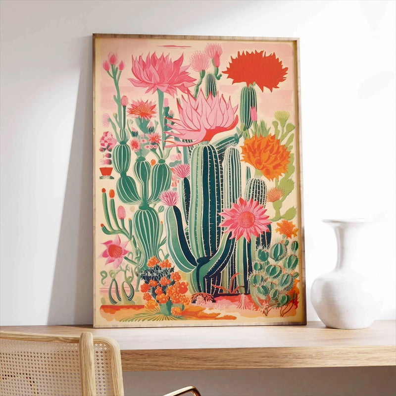 Framed artwork of cacti and flowers on a shelf with a white vase.